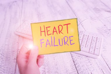 El yazısı, Kalp yetmezliği. Kavram, kalbin düzgün çalışamaması anlamına gelir. Elinde renkli kare şeklindeki kağıt, klavye ahşap zemin tutan adam..