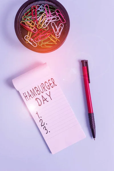 Ecriture conceptuelle montrant Hamburger Day. Texte photo d'affaires célèbre l'histoire de ce plus irrésistible de sandwichs Carnet et stationnaire avec la souris au-dessus de fond pastel . — Photo