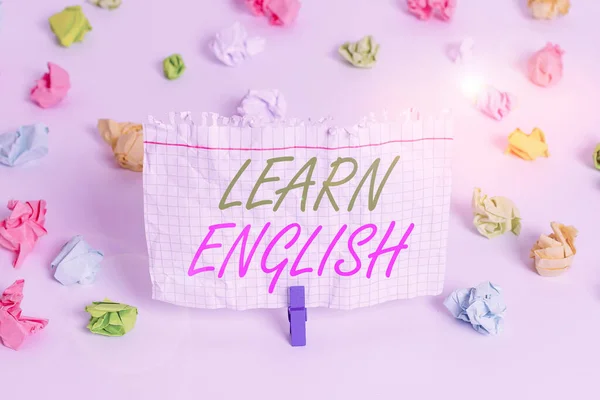 Handwriting text writing Learn English. Concept meaning gain or acquire knowledge of speaking and writing English Colored crumpled papers empty reminder white floor background clothespin.