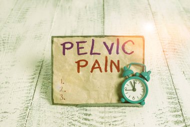 Word writing text Pelvic Pain. Business concept for Pain perceived in the area of the lower part of the abdomen Mini blue alarm clock stand tilted above buffer wire in front of notepaper.