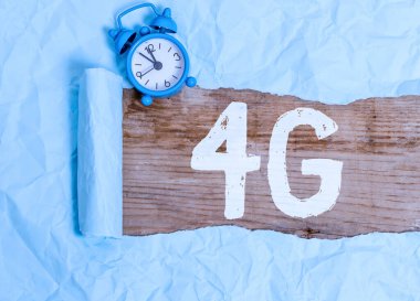 Kelime yazma metni 4G. Mobil iletişim standart kablosuz internet erişimi için iş konsepti yüksek hızlı alarmlı saat ve tahtadan yapılmış klasik masa arkaplanı üzerine yerleştirilmiş karton yırtılması.