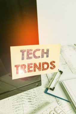 Tech Trends 'i gösteren metin işareti. Yakın zamanda popüler ve kabul gören kavramsal fotoğraf teknolojisi klavye yakınındaki siyah bilgisayar ekranına yapıştırılmış not kağıdı.
