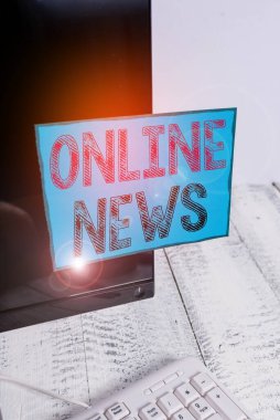 Online News 'de kelime yazma metni. Çevrimiçi gösterim kağıdı beyaz klavyenin yanındaki siyah bilgisayar monitörüne bantlanmış bir şey hakkında bilgi için iş kavramı.