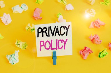 Gizlilik politikasını gösteren bir not yazıyorum. İş fotoğrafı gösterme beyanı ya da müşterilere ait verileri gösteren yasal bir belge Renkli buruşmuş kağıt boş hatırlatıcı beyaz zemin çamaşır mandalı.