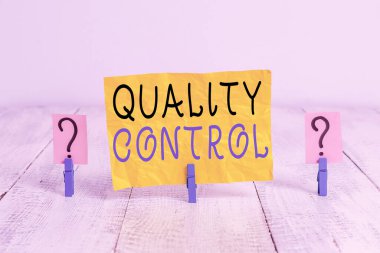 Kalite Kontrolü 'nü gösteren not yazılıyor. Analiz edilmiş ürünlerde standartların korunmasını sağlayan bir iş fotoğrafı ahşap masaya yerleştirilmiş ataçlarla parçalanmış çarşaf..