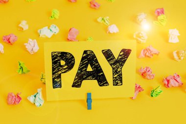 Text sign showing Pay. Conceptual photo to give money to someone for something you want to buy or for services Colored crumpled papers empty reminder white floor background clothespin.