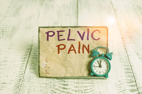 Word writing text Pelvic Pain. Business concept for Pain perceived in the area of the lower part of the abdomen Mini blue alarm clock stand tilted above buffer wire in front of notepaper.