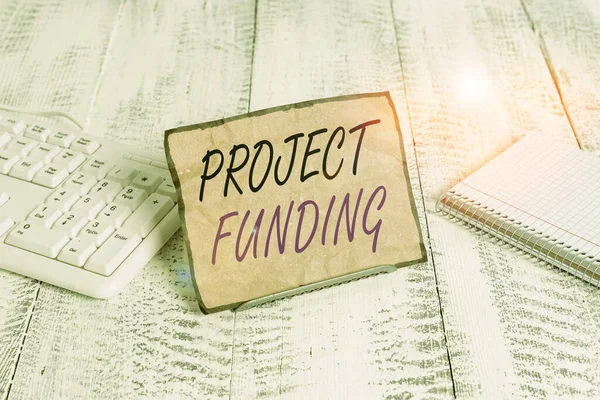 Text sign showing Project Funding. Conceptual photo capital required to undertake a project or programme Notepaper stand on buffer wire in between computer keyboard and math sheets. — Φωτογραφία Αρχείου