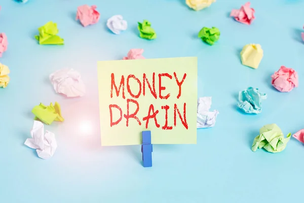Word writing text Money Drain. Business concept for To waste or squander money Spend money foolishly or carelessly Colored crumpled papers empty reminder blue floor background clothespin.