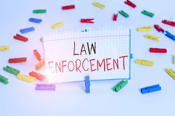 Text sign showing Law Enforcement. Conceptual photo activity of making certain that the laws of an area are obey Colored clothespin papers empty reminder white floor background office.