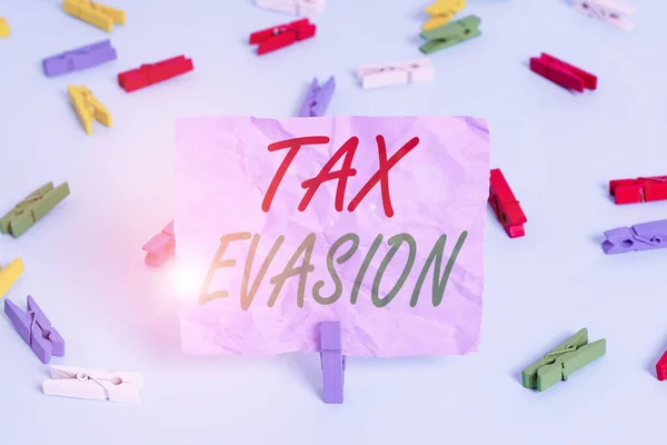 Word writing text Tax Evasion. Business concept for the failure to pay or the deliberate underpayment of taxes Colored clothespin papers empty reminder blue floor background office pin.