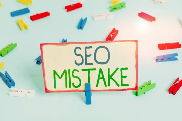 Handwriting text Seo Mistake. Concept meaning action or judgment that is misguided or wrong in search engine Colored clothespin papers empty reminder blue floor background office pin. — Stockfoto