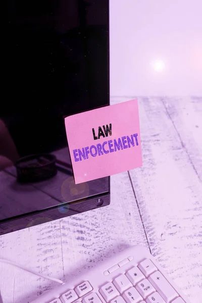 法執行機関を示す概念的な手書き。エリアの法律が遵守されていることを確認する活動を紹介するビジネス写真白いキーボードの近くに表記用紙コンピュータのモニター画面. — ストック写真