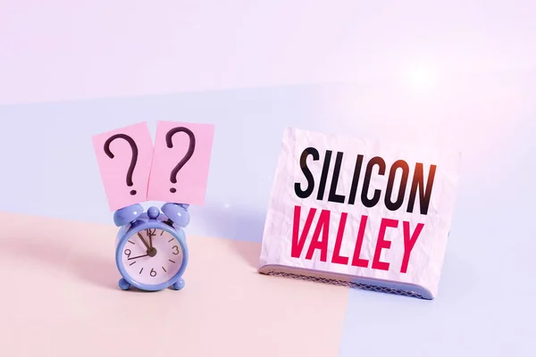 Writing note showing Silicon Valley. Business photo showcasing home to analysisy startup and global technology companies Alarm clock beside a Paper sheet placed on pastel backdrop.