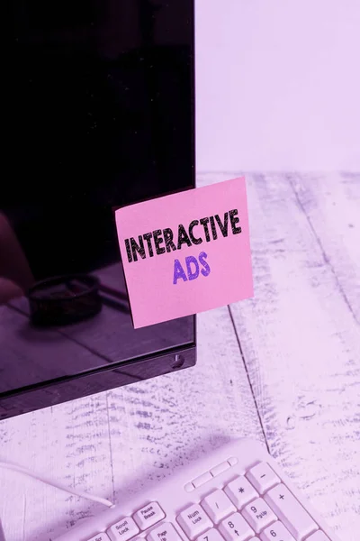 Conceptual hand writing showing Interactive Ads. Business photo showcasing uses interactive media to communicate with consumers Notation paper computer monitor screen near white keyboard.