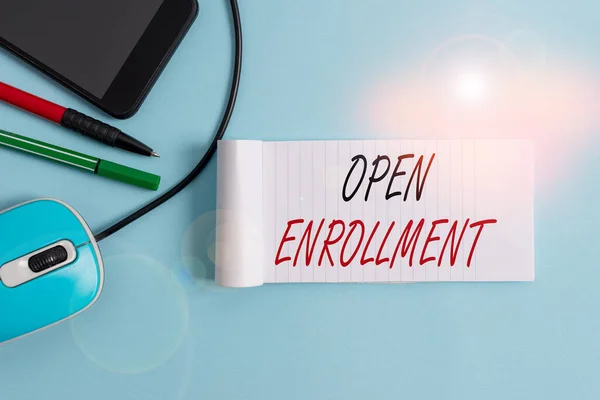 Text sign showing Open Enrollment. Conceptual photo policy of allowing qualifying students to enroll in school Notebook and writing equipment with modern gadget above pastel backdrop. — Zdjęcie stockowe