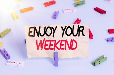 Text sign showing Enjoy Your Weekend. Conceptual photo wishing someone that something nice will happen at holiday Colored clothespin papers empty reminder blue floor background office pin.