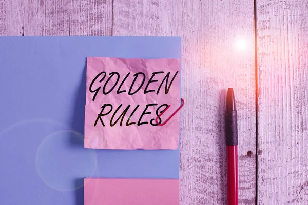 Text sign showing Golden Rules. Conceptual photo basic principle that should always follow to ensure success Wrinkle paper and cardboard plus stationary placed above wooden background. — ストック写真