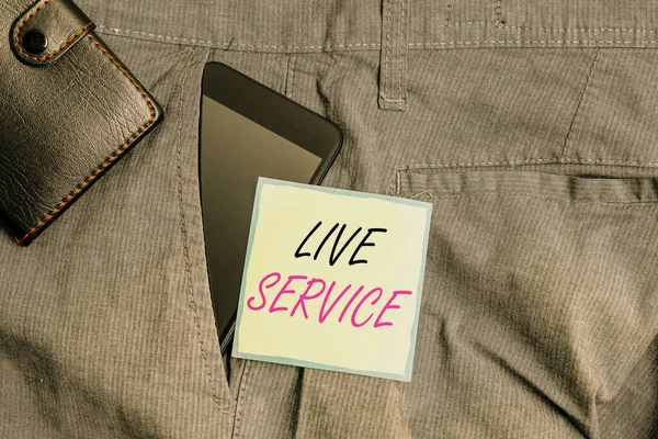 Text sign showing Live Service. Conceptual photo Extending or providing help to others in verbal or action way Smartphone device inside trousers front pocket with wallet and note paper. — ストック写真