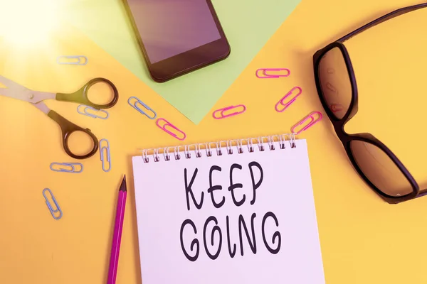 Writing note showing Keep Going. Business photo showcasing make an effort to live normally when in a difficult situation Sheet pencil smartphone scissors eyeglasses notepad color background. — Stockfoto