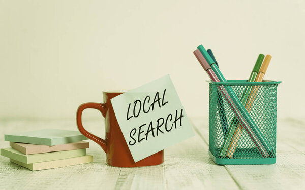 Handwriting text writing Local Search. Conceptual photo searches of a structured database of local business listings Coffee cup blank sticky note pens metal holder stacked pads wooden table