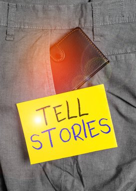 Tell Stories 'i gösteren bir not yazıyorum. Olay hakkında birine bir şeyler anlatmak için resmi fotoğraf sergisi resmi. Pantolonun ön cebinde not kağıdının yanında küçük bir cüzdan..