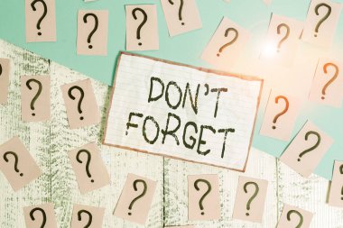 El yazısı metni, unutma. Kavram anlamı, birisine önemli bir gerçeği veya detayı hatırlatmak için kullanılır. Ahşap masanın üzerinde kalın kartonla yazılmış ve parçalanmış kağıtlar..