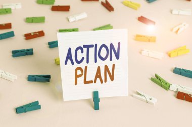 Kelime yazma Eylem Planı. Hedeflere ulaşmak için gereken eylemleri özetleyen ayrıntılı plan için iş konsepti Renkli çamaşır iğnesi kağıtları boş hatırlatıcı pembe zemin ofis broşu.