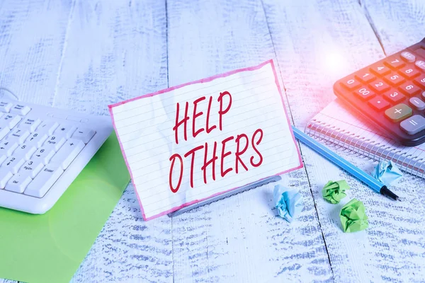 Handwriting text Help Others. Concept meaning the action of helping someone to do something or assistance Notepaper stand on buffer wire in between computer keyboard and math sheets. — Stockfoto