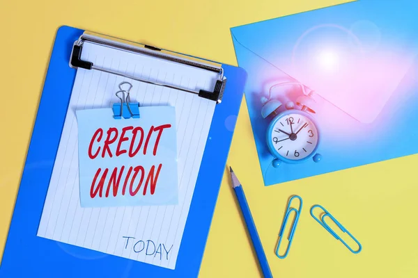 Writing note showing Credit Union. Business photo showcasing cooperative association that makes small loans to members Clipboard sheet note pencil clips clock envelop colored background.