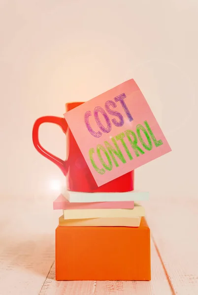 Text sign showing Cost Control. Conceptual photo practice of identifying and reducing business expenses Coffee cup blank sticky note stacked note pads square box wooden table.