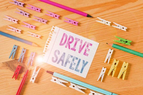 Writing note showing Drive Safely. Business photo showcasing you should follow the rules of the road and abide laws Colored clothespin papers empty reminder wooden floor background office.