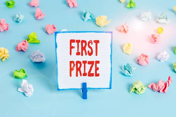 Handwriting text First Prize. Concept meaning the most desirable or grand prize offered for the overall winner Colored crumpled papers empty reminder blue floor background clothespin.