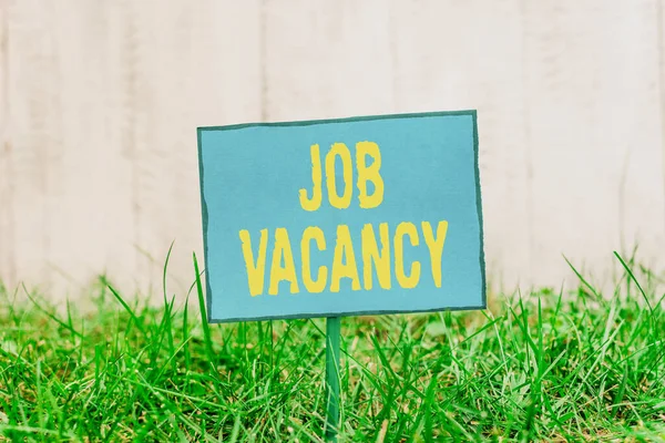 Conceptual hand writing showing Job Vacancy. Business photo showcasing job that no one is doing and available for someone to do Plain paper attached to stick and placed in the grassy land.