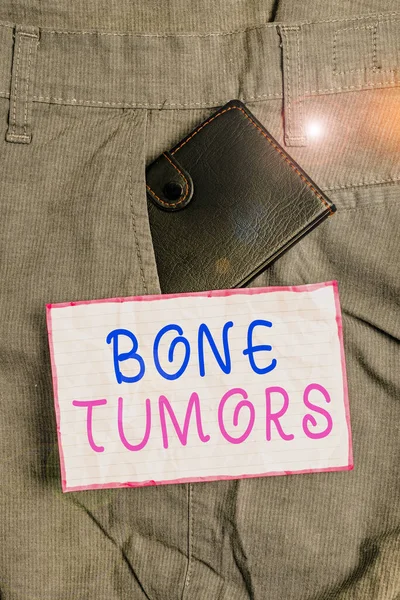 Text sign showing Bone Tumors. Conceptual photo can be either benign or malignant growths found in the bone Small little wallet inside man trousers front pocket near notation paper.