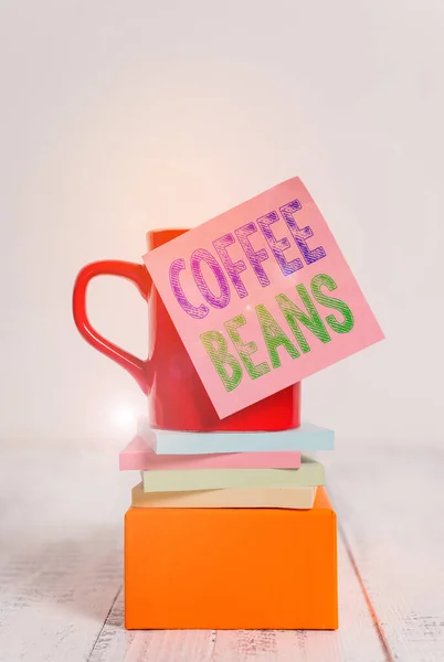 Text sign showing Coffee Beans. Conceptual photo pit inside the red or purple fruit often referred as a cherry Coffee cup blank sticky note stacked note pads square box wooden table. — 스톡 사진