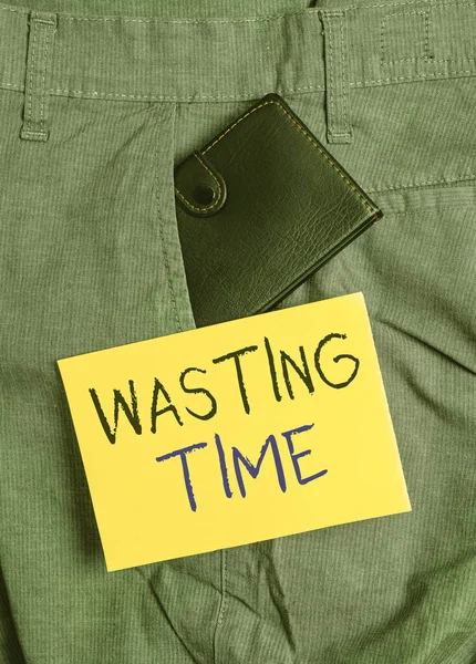 Writing note showing Wasting Time. Business photo showcasing act of spending time doing something that is unnecessary Small wallet inside trouser front pocket near notation paper.