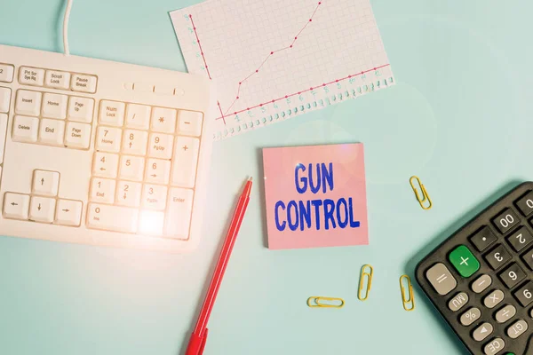 Handwriting text writing Gun Control. Concept meaning legal measure intended to restrict the possession of guns Paper blue desk computer keyboard office study notebook chart numbers memo.