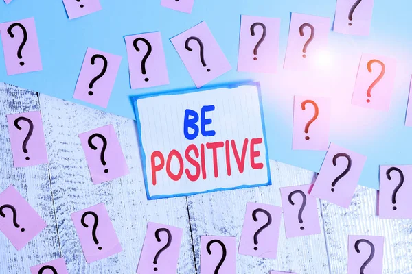 Writing note showing Be Positive. Business photo showcasing giving cause for hope and confidence Without any doubt Scribbled and crumbling papers with thick cardboard above wooden table.