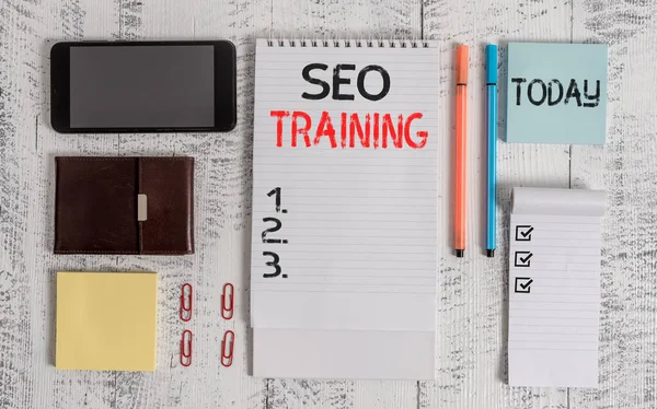 Tekst schrijven Seo Training. Business concept voor het leren van specifieke kennis verbeteren van de prestaties in de huidige rollen Smartphone portemonnee plakkerige notities clips notebook pennen notitieblok houten tafel. — Stockfoto