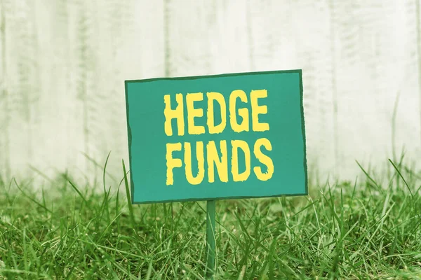 Conceptual hand writing showing Hedge Funds. Business photo showcasing basically a fancy name for an alternative investment partnership Plain paper attached to stick and placed in the grassy land. — Stok fotoğraf