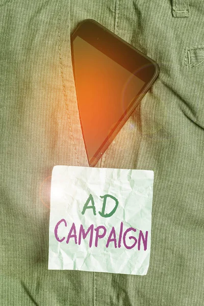 Writing note showing Ad Campaign. Business photo showcasing an organized course of action to promote a product or service Smartphone device inside trousers front pocket note paper. — Stock Photo, Image