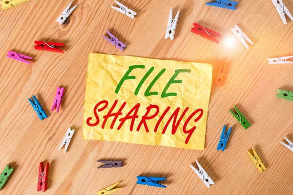 Writing note showing File Sharing. Business photo showcasing transmit files from one computer to another over a network Colored clothespin papers empty reminder wooden floor background office.