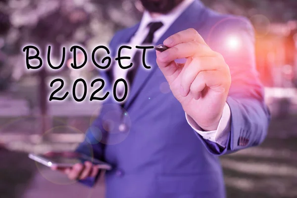Textzeichen für den Haushalt 2020. Konzeptionelle Foto-Schätzung von Einnahmen und Ausgaben für nächstes oder aktuelles Jahr Geschäftsmann hält Laptop und Stift in den Kopierraum. — Stockfoto