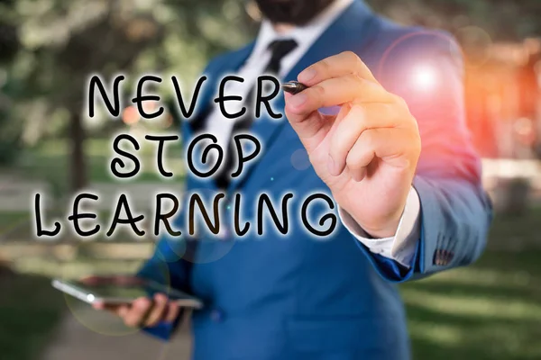 Znak tekstowy pokazujący "Never Stop Learning". Konceptualne zdjęcie badaj zdobywanie nowej wiedzy lub materiałów Biznesmen trzyma laptopa i długopis wskazując w przestrzeń kopiowania. — Zdjęcie stockowe