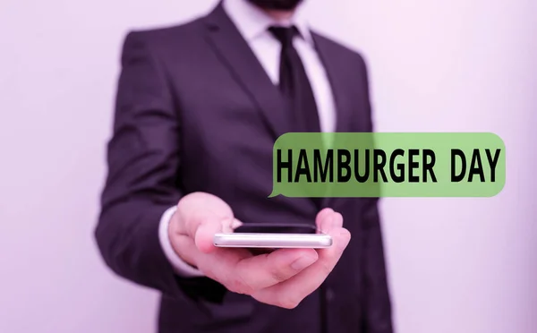 Texte écrit Hamburger Day. Concept d'affaires pour célèbre l'histoire de ce plus irrésistible des sandwichs costume de travail formel homme tenue smart salut technologie smartphone utiliser une main . — Photo