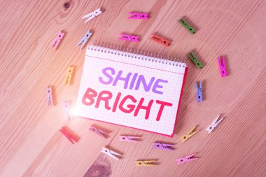 Shine Bright 'ın el yazısı. Kavram demek, zor bir durumda yaşamak için çabalamak demektir. Renkli çamaşır iğnesi kağıtları boş hatırlatıcı ahşap zemin ofis.