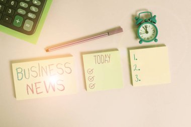 Business News 'un el yazısı. Bir gazete ya da haber dergisinde bildirilen bilgi anlamına gelen kavram. Çok renkli notlar, alarmlı saat hesap makinesi tablosu renkli arkaplan.