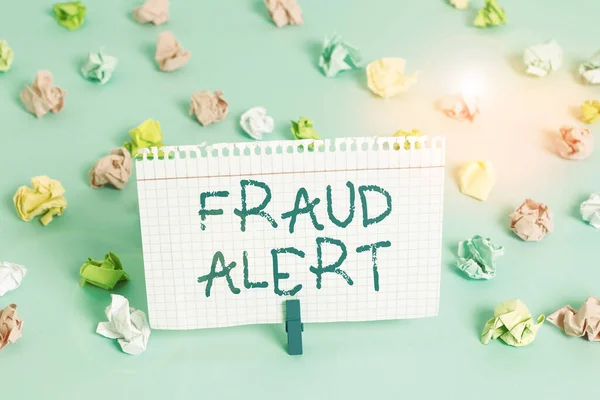 Conceptual hand writing showing Fraud Alert. Business photo showcasing security alert placed on credit card account for stolen identity Colored crumpled papers empty reminder blue floor clothespin.