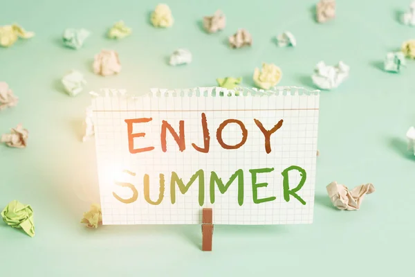 Woord schrijven tekst Geniet van de zomer. Zakelijk concept voor het nemen van een pauze van school en het doorbrengen van vakantie op het strand Gekleurde verfrommelde rechthoek vormige herinnering papier lichtblauwe achtergrond. — Stockfoto